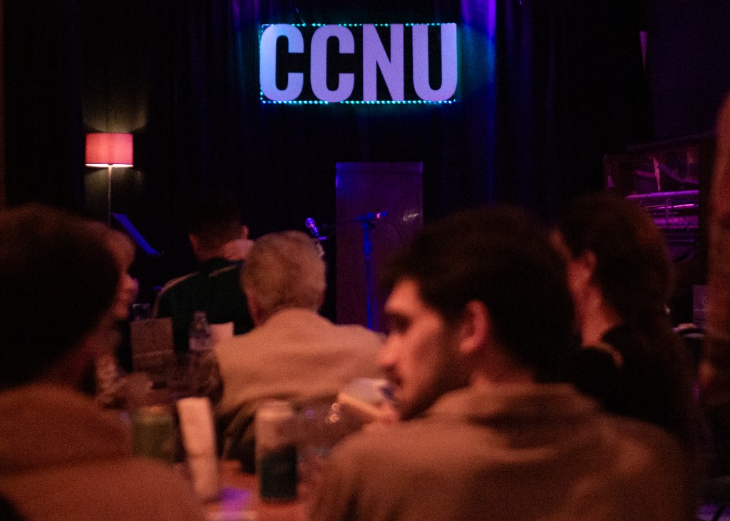 Letrero CCNU iluminado con público en la sala